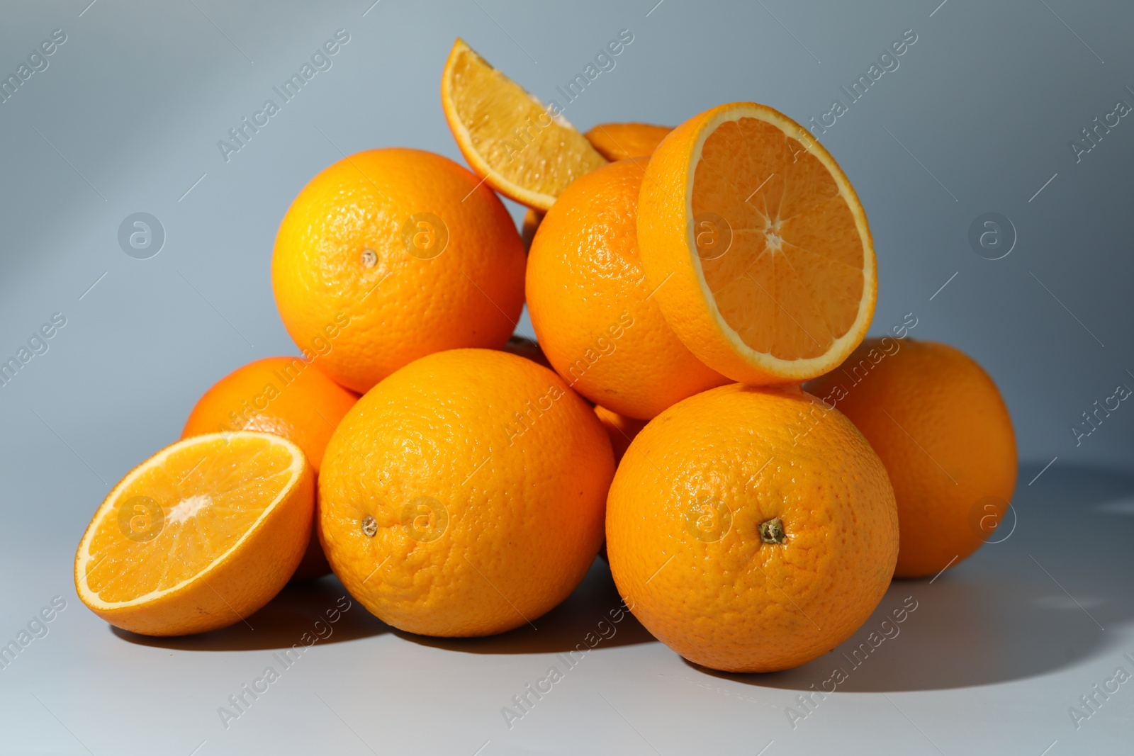 Photo of Many whole and cut oranges on grey background