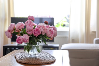 Beautiful pink peonies in vase on table at home, space for text. Interior design