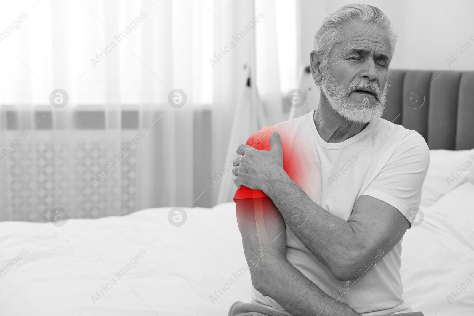 Image of Arthritis symptoms. Man suffering from pain in his shoulder indoors, space for text. Black and white effect with red accent in painful area