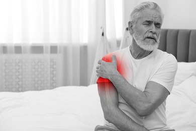 Arthritis symptoms. Man suffering from pain in his shoulder indoors, space for text. Black and white effect with red accent in painful area
