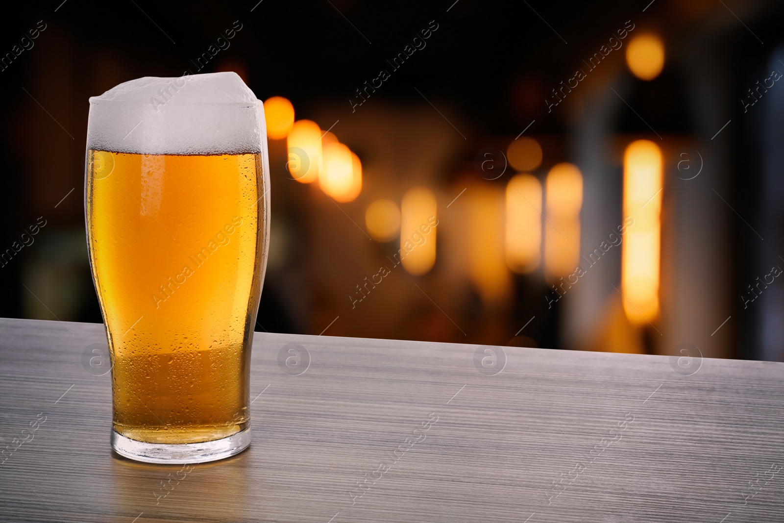 Image of Fresh cold beer on wooden table in pub, space for text 