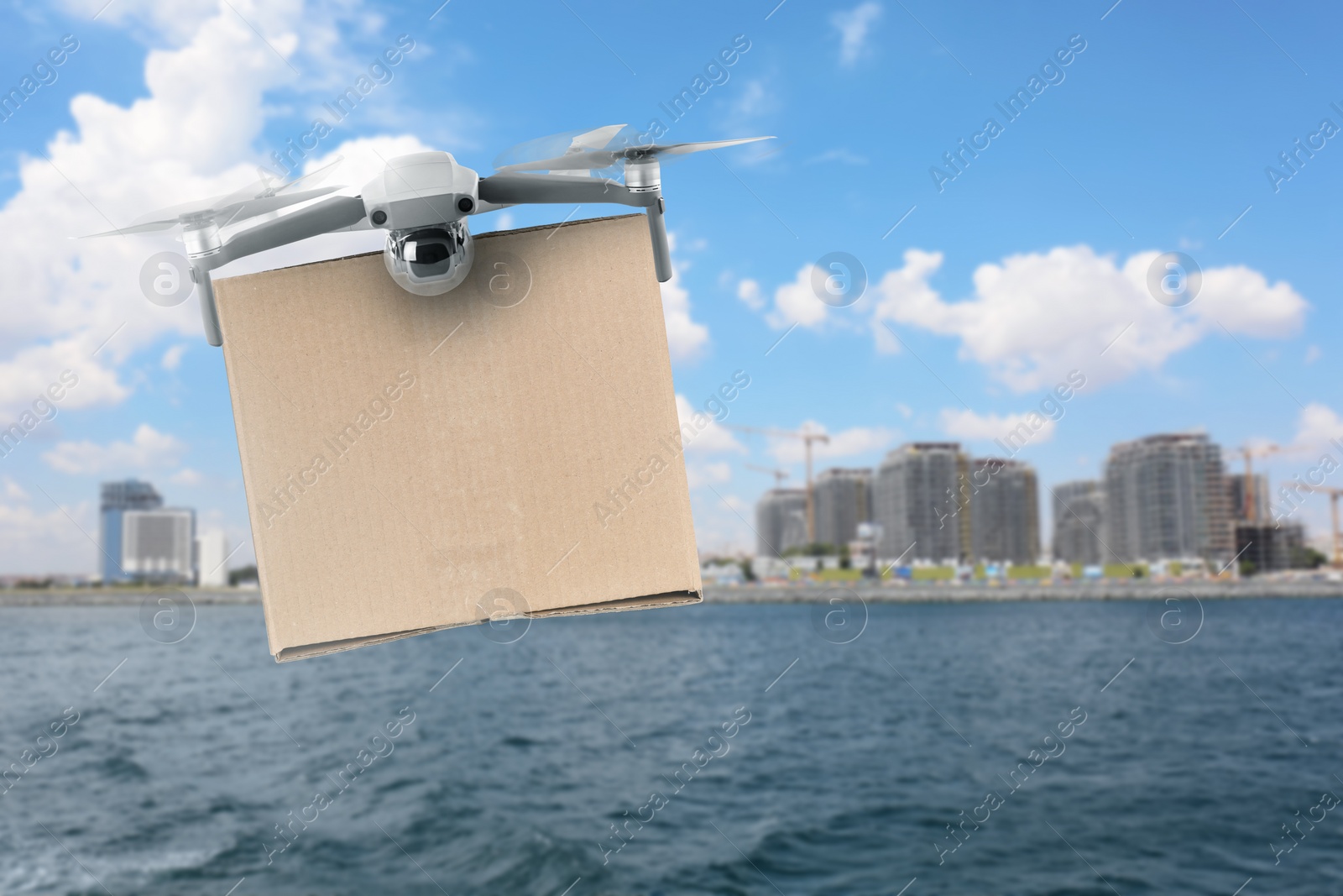 Image of Modern drone with carton box flying above sea on sunny day. Delivery service 