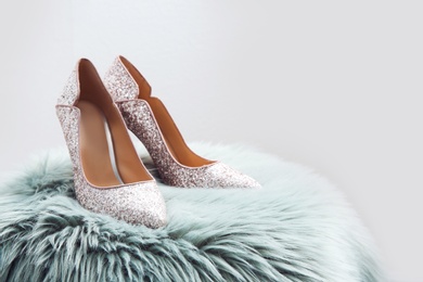 Photo of Stylish female shoes on fur against light background. Space for text