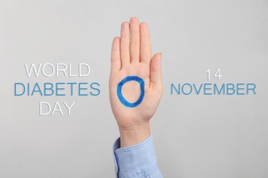 Image of Woman showing blue circle drawn on palm against light grey background, closeup. World Diabetes Day