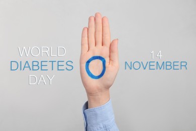 Woman showing blue circle drawn on palm against light grey background, closeup. World Diabetes Day