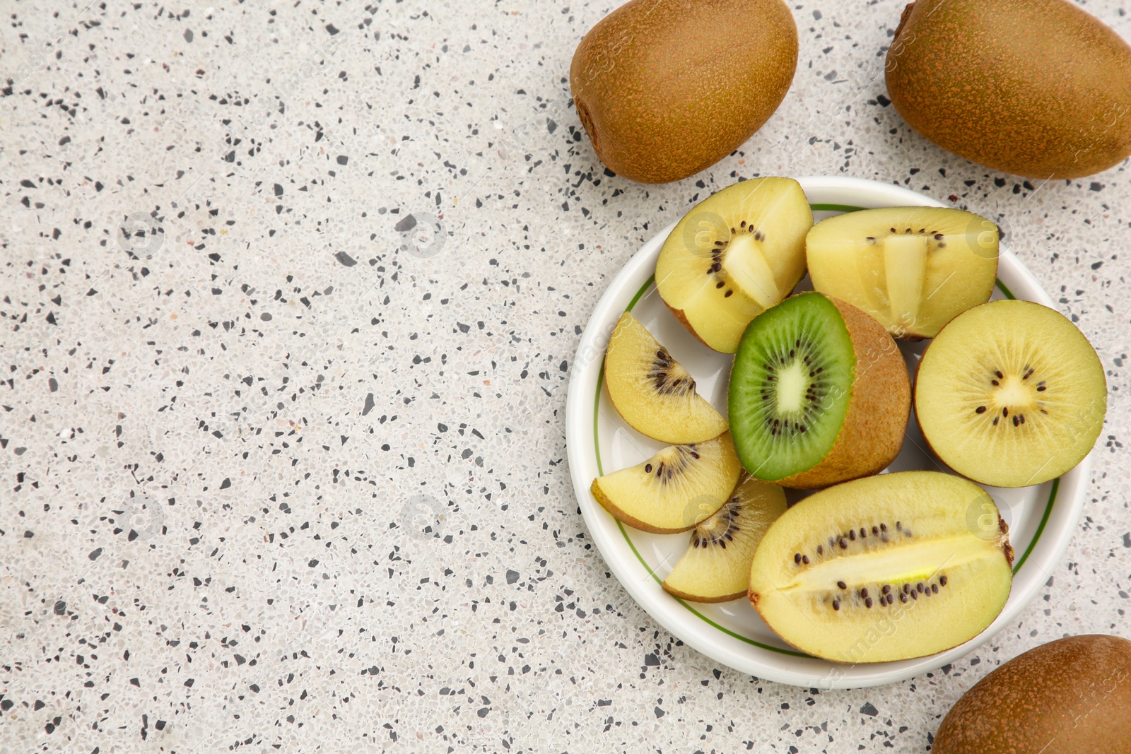 Photo of Whole and cut fresh kiwis on white table with pattern, flat lay. Space for text