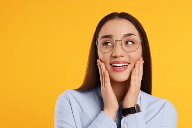 Beautiful woman wearing glasses on orange background, space for text