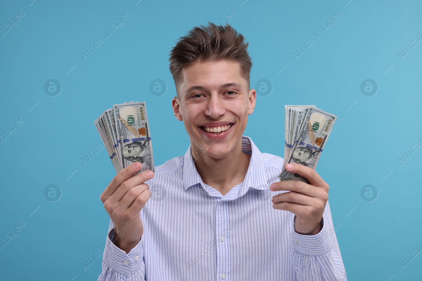 Photo of Happy man with dollar banknotes on light blue background