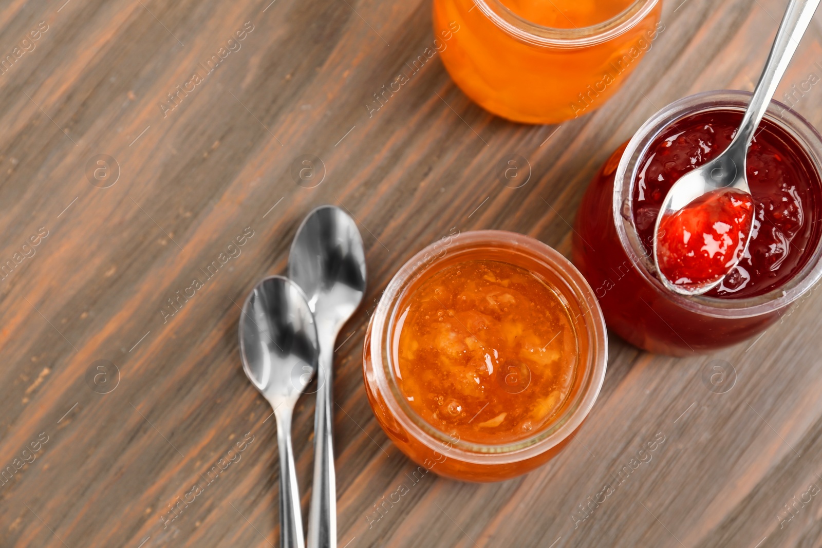 Photo of Jars with tasty sweet jam on wooden table