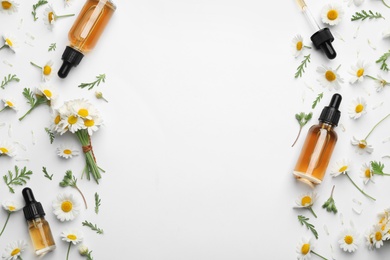 Photo of Chamomile flowers and cosmetic bottles of essential oil on white background, top view. Space for text