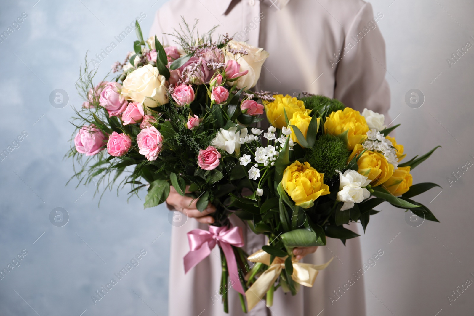 Photo of Woman with beautiful bouquets on light blue background, closeup
