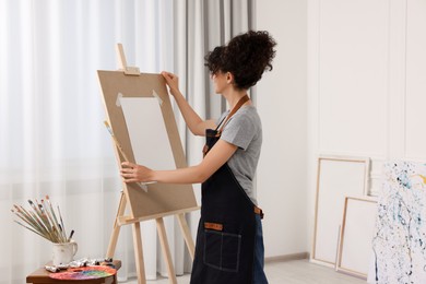 Photo of Young woman with brush adjusting easel in studio