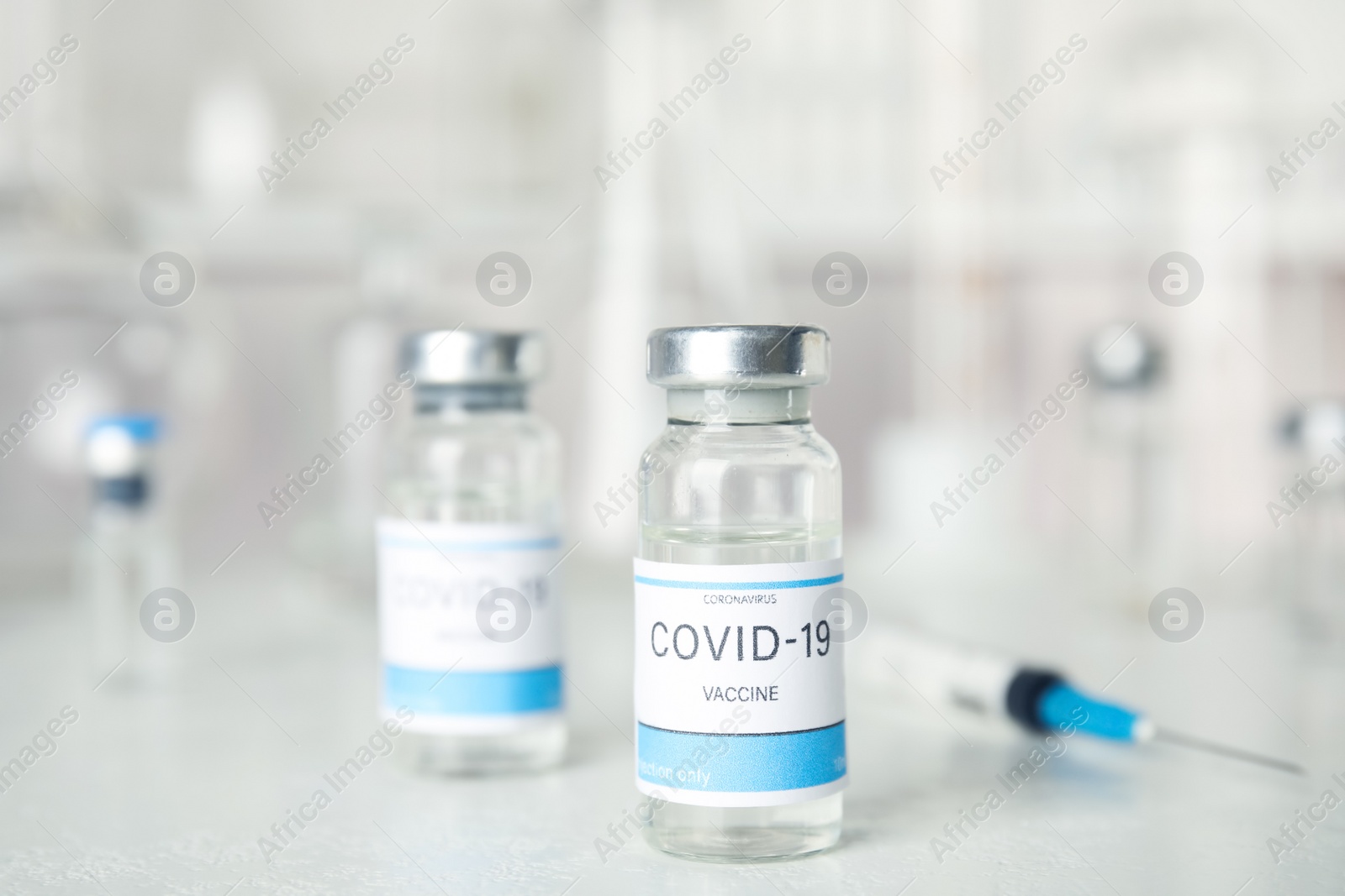 Photo of Vials and syringe with coronavirus vaccine on light table