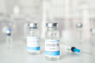 Vials and syringe with coronavirus vaccine on light table