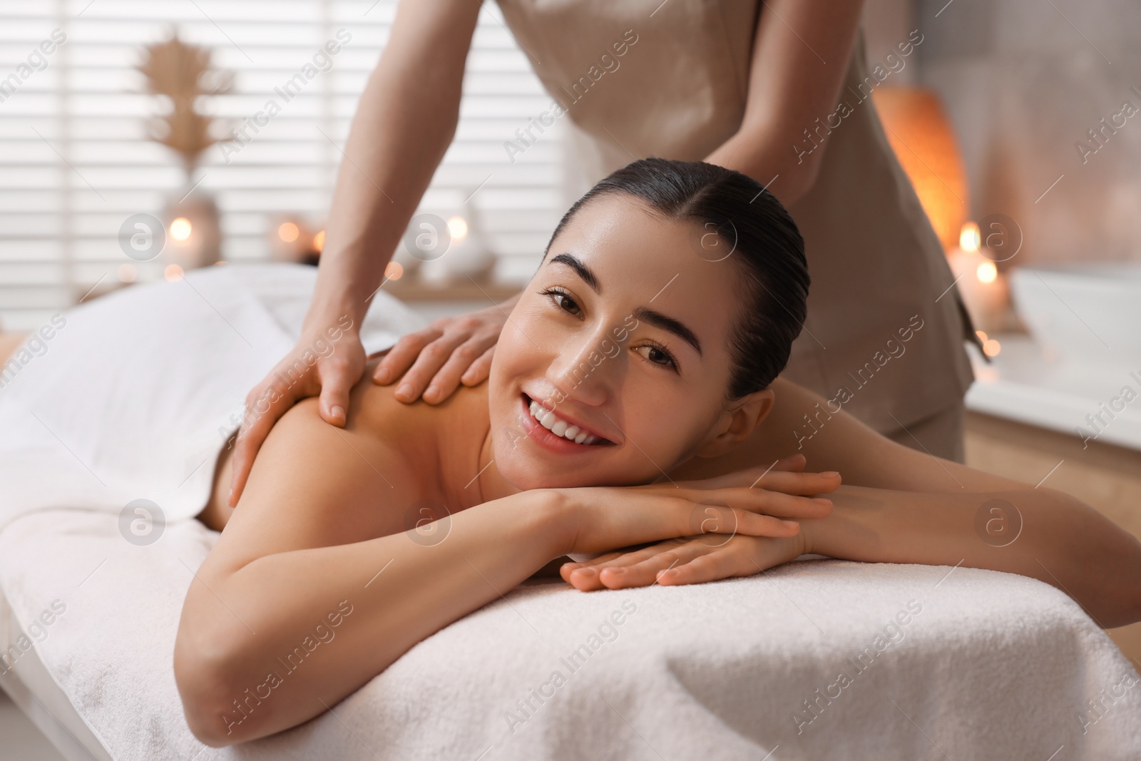 Photo of Woman receiving back massage on couch in spa salon