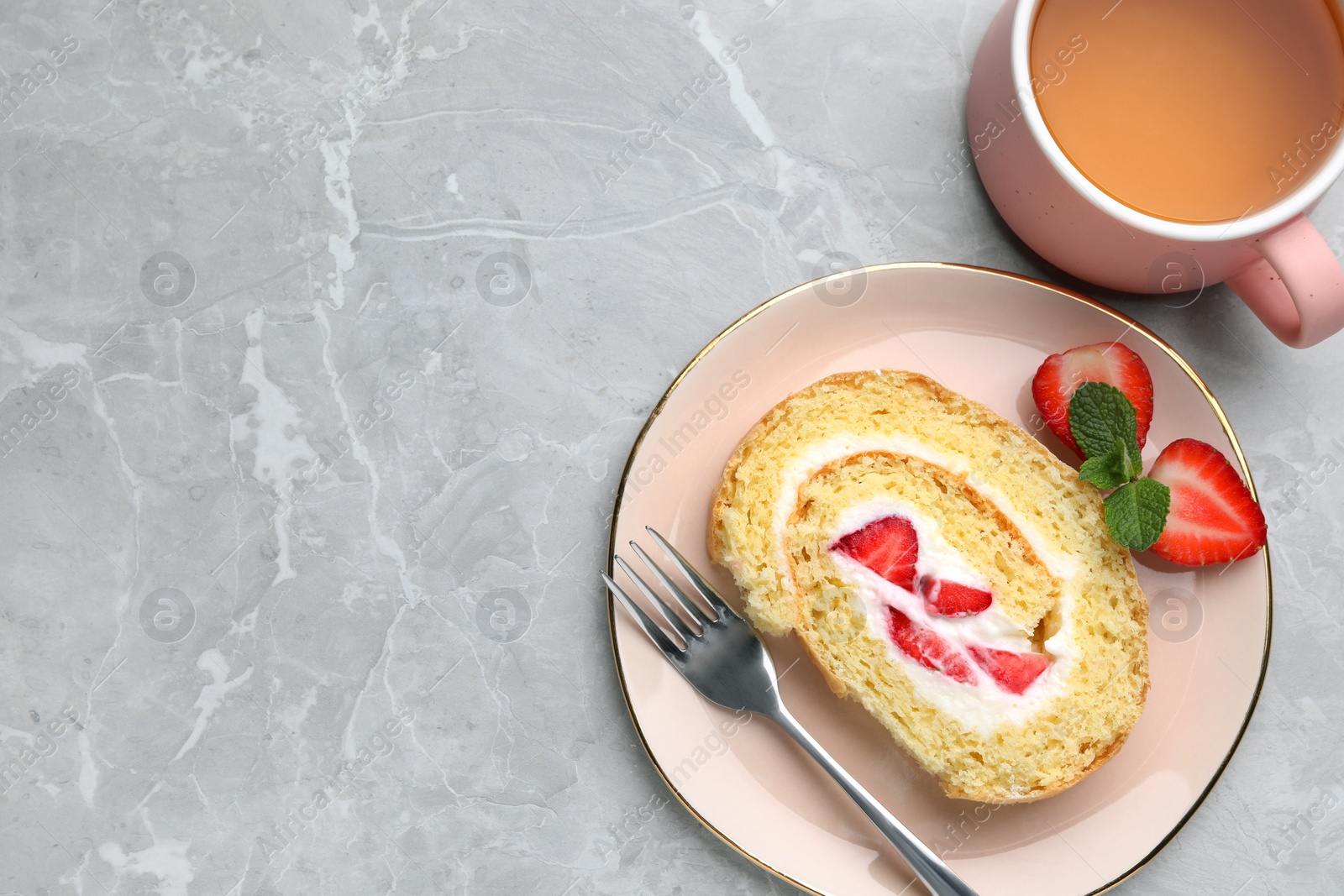 Photo of Slice of delicious sponge cake roll with strawberries and cream served on light grey table, flat lay. Space for text