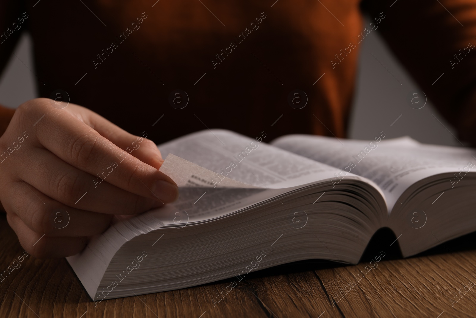 Photo of Woman reading Bible at wooden table, closeup