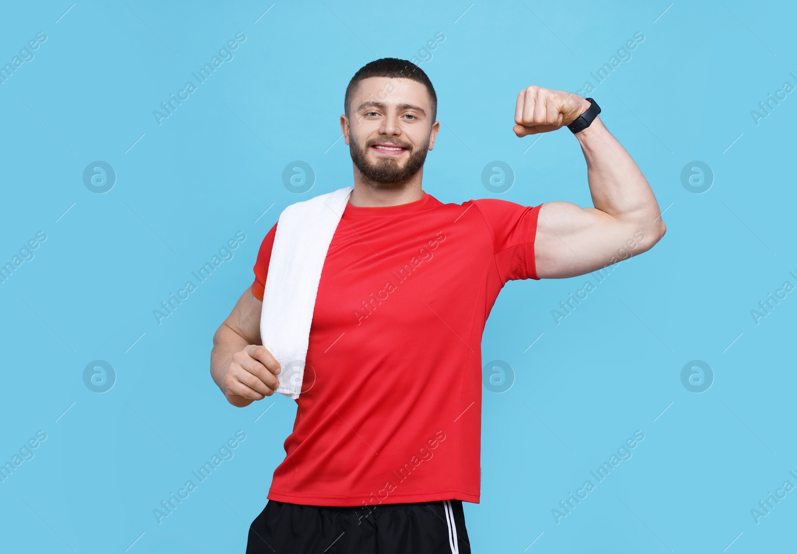 Photo of Handsome sportsman with white towel showing muscles on light blue background, space for text