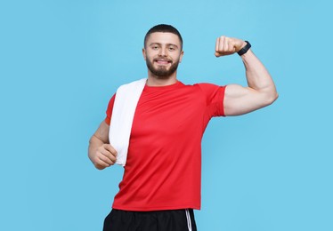 Photo of Handsome sportsman with white towel showing muscles on light blue background, space for text