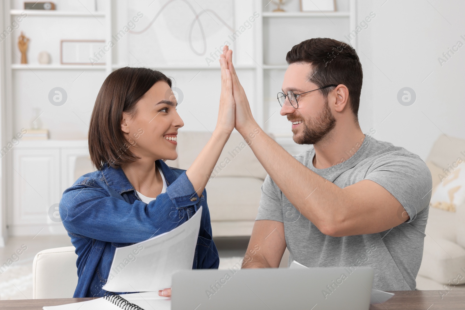 Photo of Young couple with papers discussing pension plan at wooden table indoors