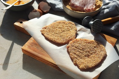 Cooking schnitzel. Raw pork chops in bread crumbs, meat mallet and ingredients on grey table