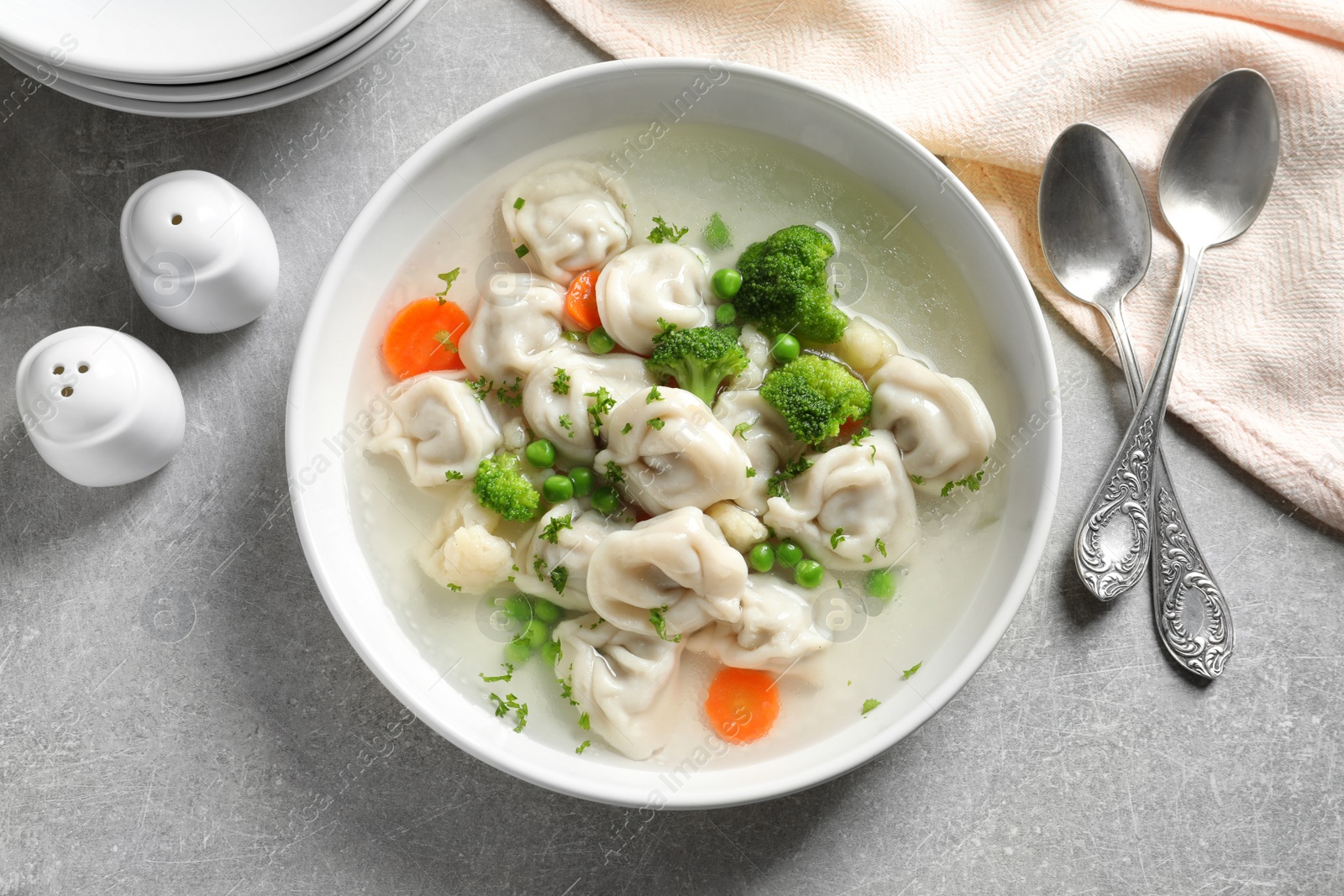 Photo of Bowl of tasty dumplings served on grey table, flat lay