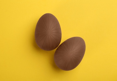 Sweet chocolate eggs on yellow background, flat lay