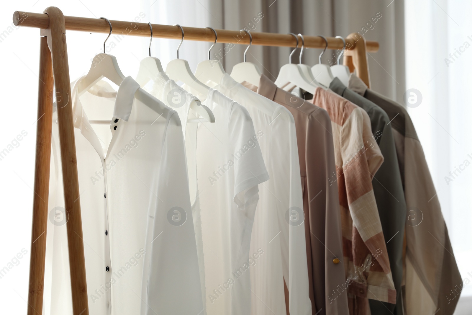 Photo of Different stylish clothes on rack in room