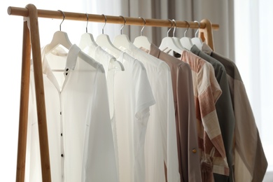 Photo of Different stylish clothes on rack in room