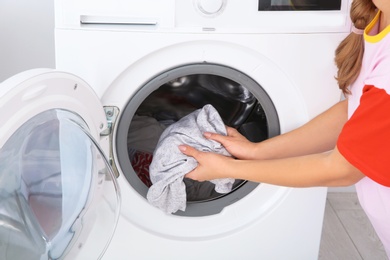 Photo of Young woman using washing machine, closeup. Laundry day