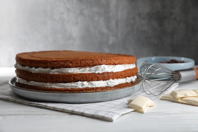 Photo of Delicious homemade layer cake and chocolate on white wooden table, closeup