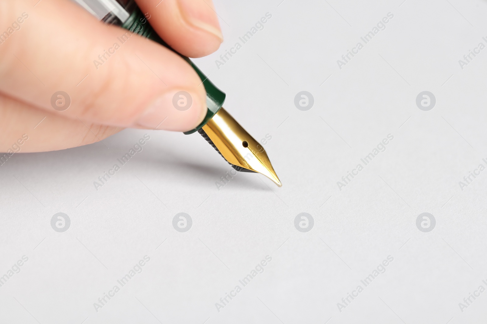 Photo of Woman with fountain pen above white paper, closeup. Space for text