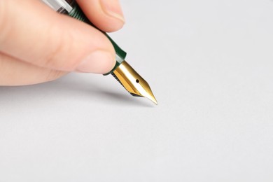 Woman with fountain pen above white paper, closeup. Space for text