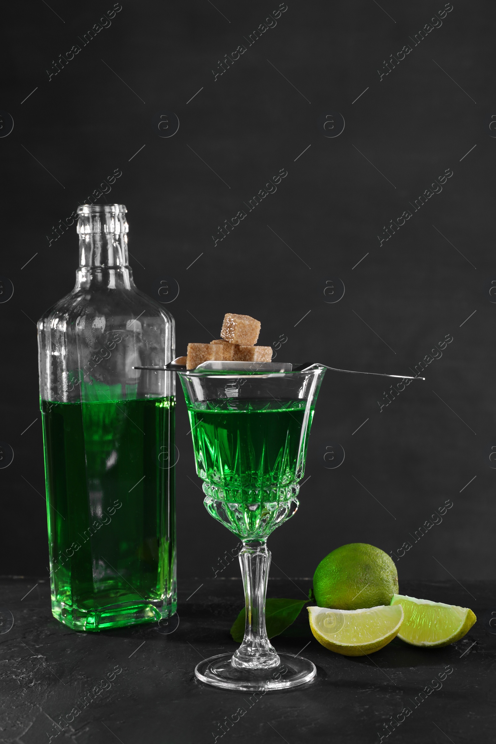 Photo of Absinthe, brown sugar and lime on black table. Alcoholic drink