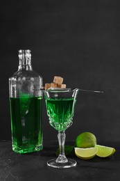 Photo of Absinthe, brown sugar and lime on black table. Alcoholic drink