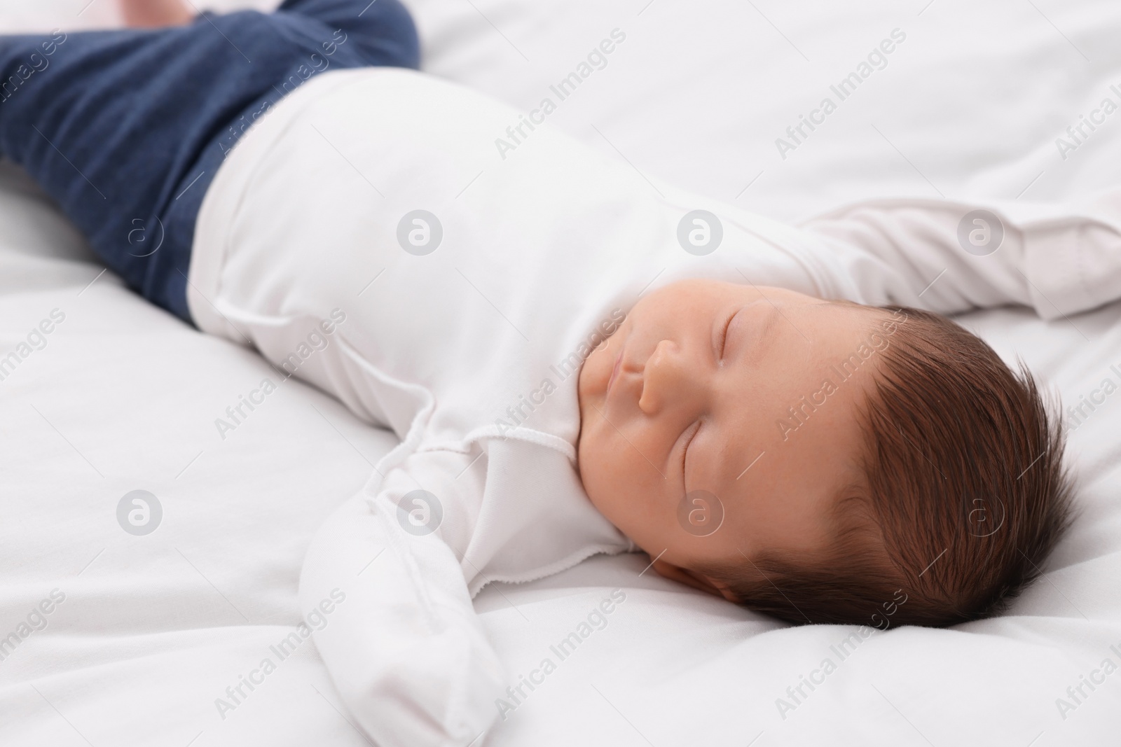 Photo of Cute newborn baby sleeping on white blanket, closeup