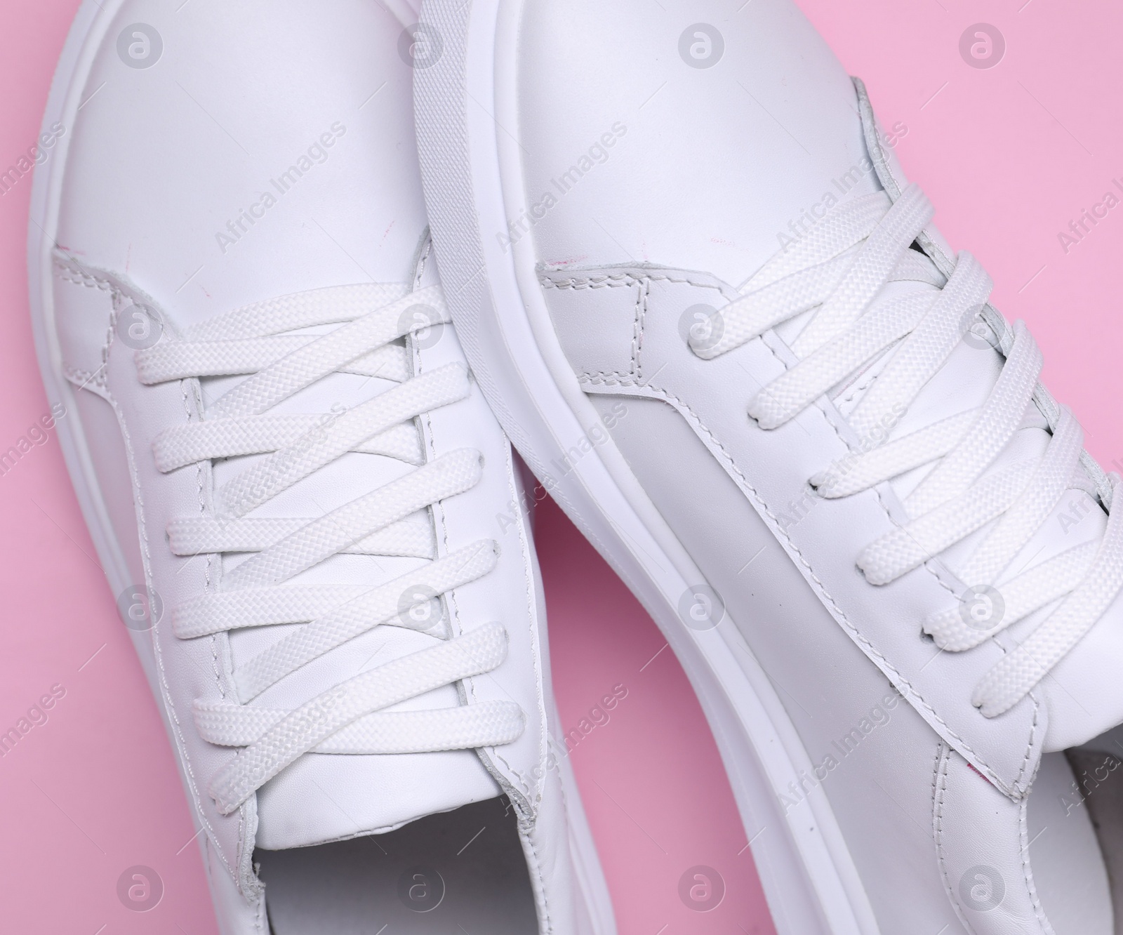 Photo of Pair of stylish white sneakers on pink background, top view