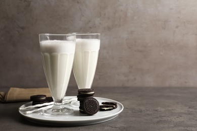 Photo of Glasses of milk with chocolate cookies on table against grey background, space for text