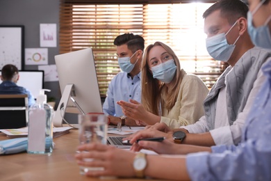 Photo of Coworkers with masks in office. Protective measure during COVID-19 pandemic