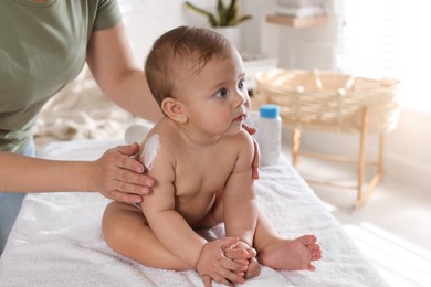 Photo of Mother applying body cream on her little baby at home, closeup