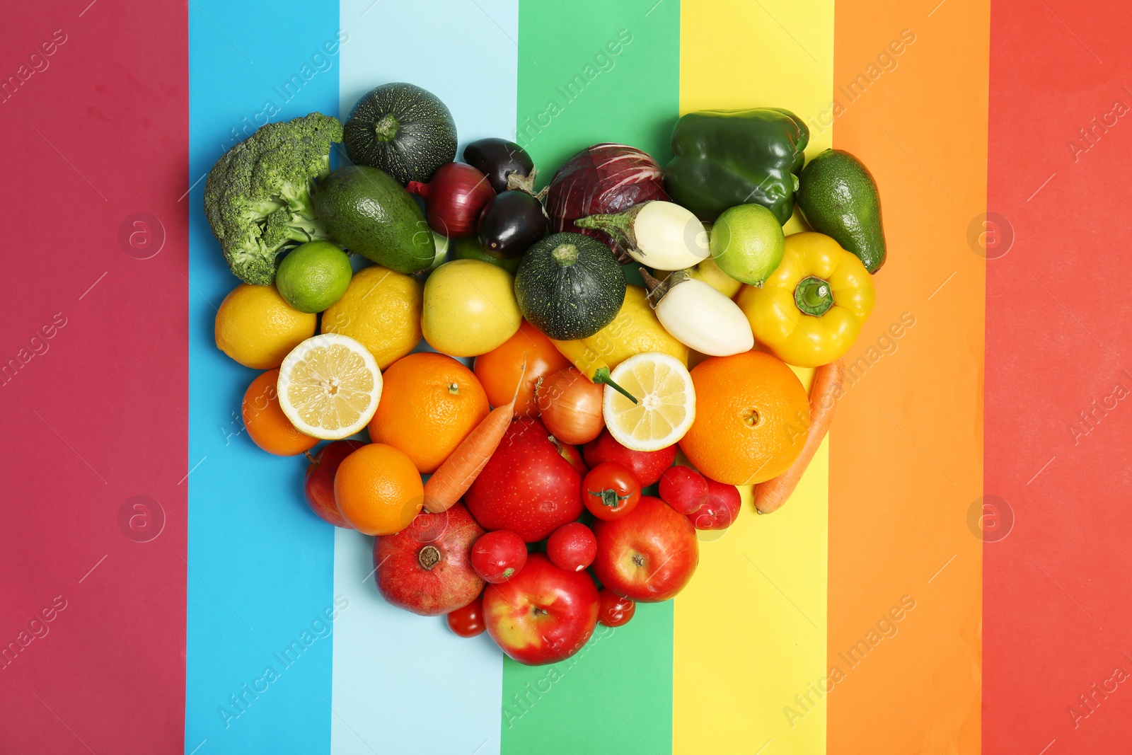 Photo of Rainbow heart made of fruits and vegetables on color background