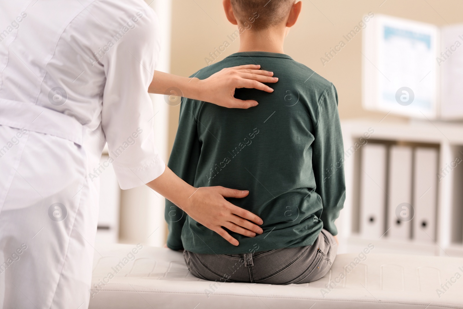 Photo of Chiropractor examining child with back pain in clinic, closeup