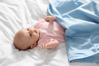 Photo of Cute little baby lying on white sheets