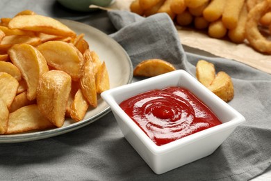 Photo of Delicious baked potato wedges and ketchup on table, closeup