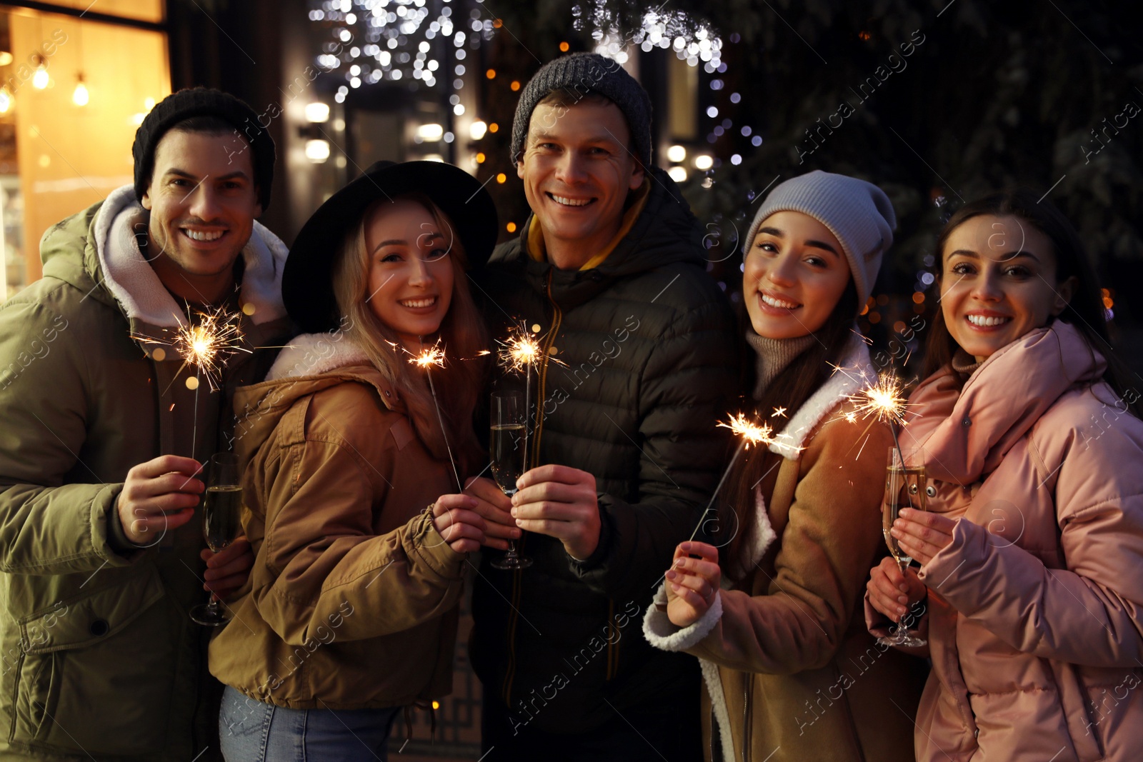 Photo of Group of happy friends with sparklers and champagne at winter fair