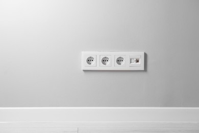Photo of Electric power sockets on light grey wall indoors