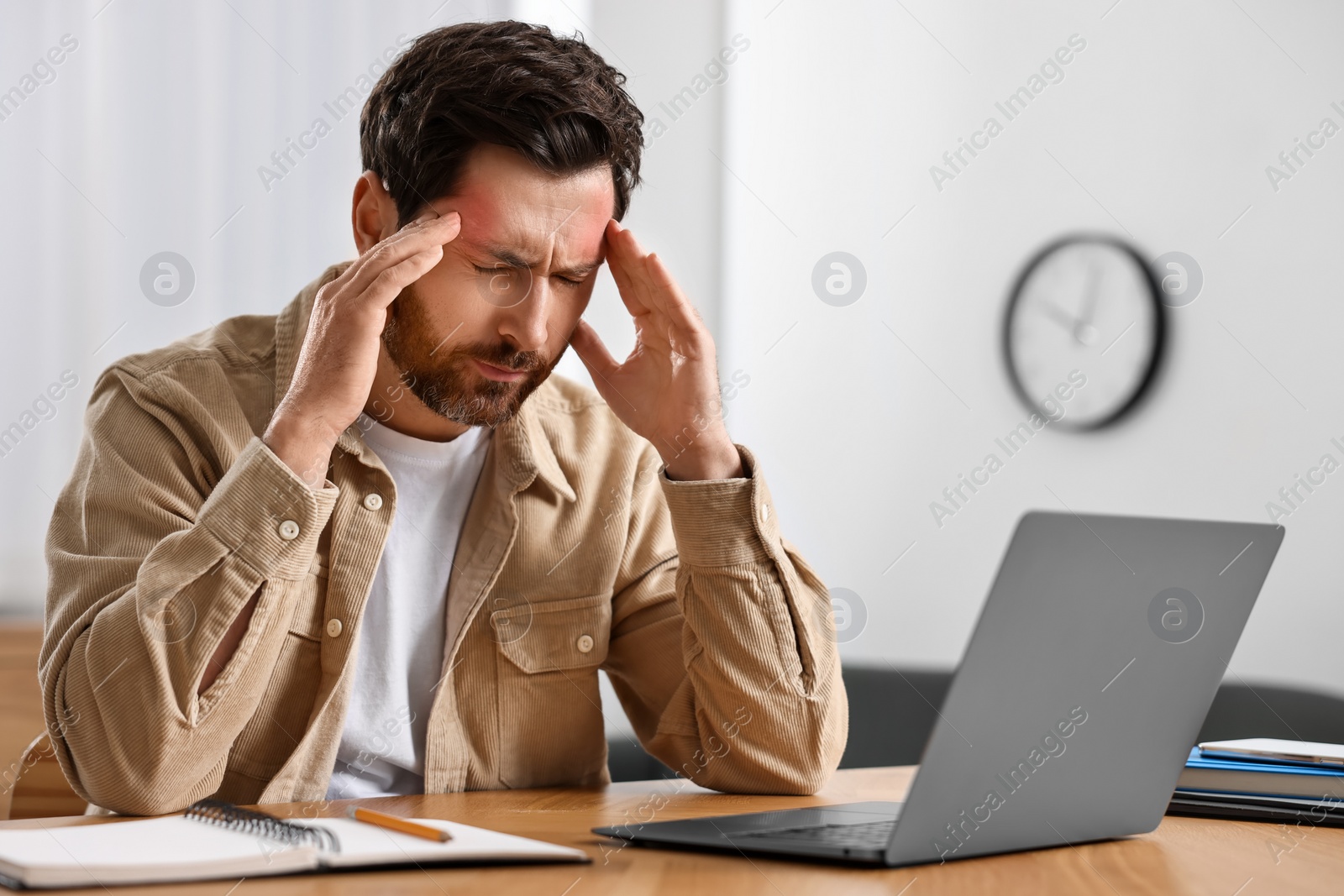 Image of Tired man suffering from headache at workplace indoors