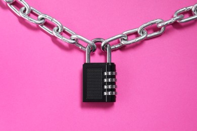 Photo of Steel combination padlock and chain on pink background, top view