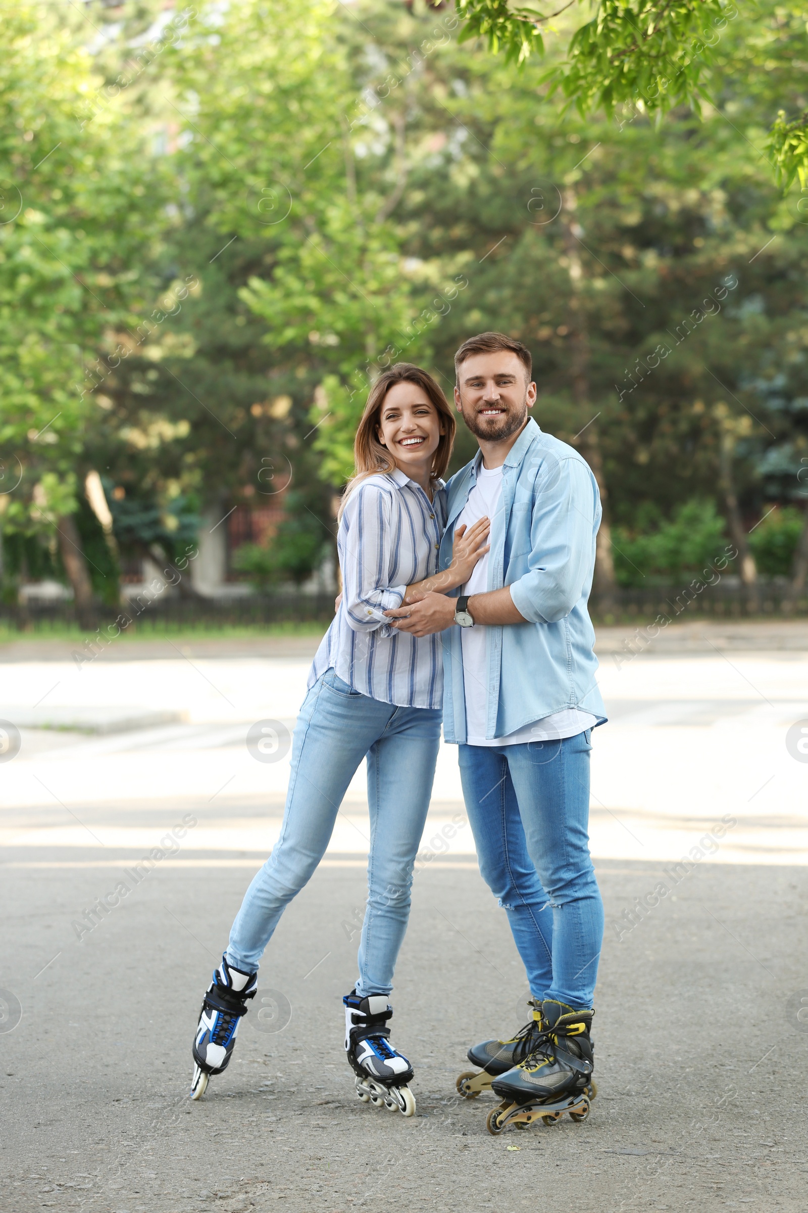 Photo of Young happy couple roller skating in summer park