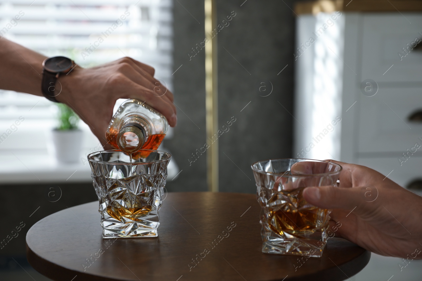 Photo of Young men drinking whiskey together at home, closeup